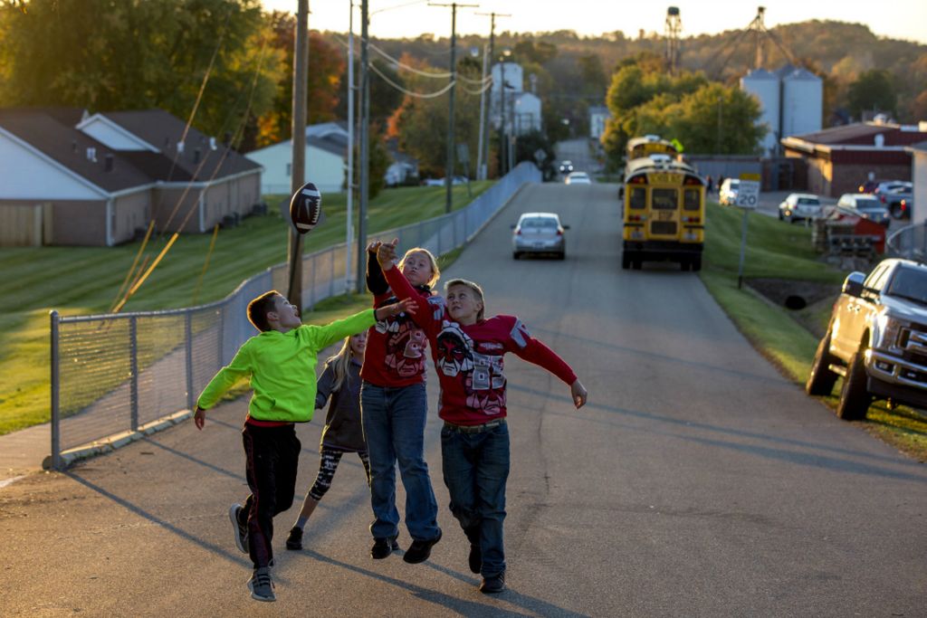 First Place, Ron Kuntz Sports Photographer of the Year - Jessica Phelps / Newark AdvocateJessi Paxton, Brooklyn White and Wyatt McInturff all reach to catch a football while playing in the street next to the Utica football field October 16, 2020. The kids were playing while their parents watched the game from their trucks, outside the fence. Because of COVID restrictions on family members were allowed inside the stadium to watch games. 