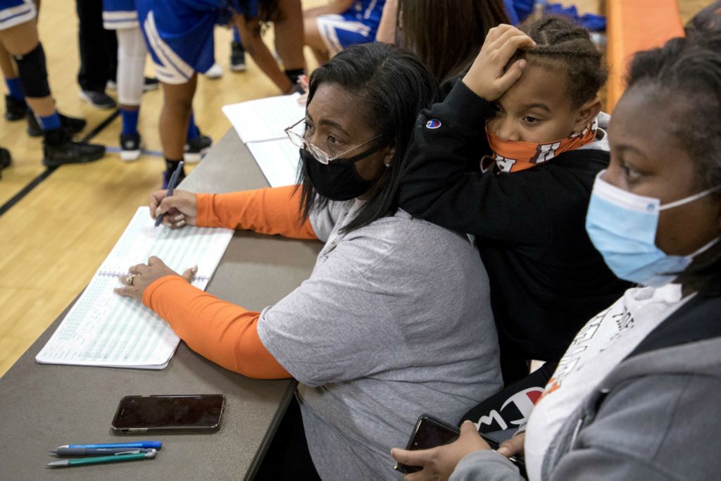 First Place, Ron Kuntz Sports Photographer of the Year - Jessica Phelps / Newark AdvocateShela Croom keeps stats at a Heath 7th and 8th grade school games her daughters, Tavia and Taya coach December 10, 2020. Her grandson, Kam leans on her trying to stay awake during the games. The Croom family has put down roots in Heath with Shela Croom coaching high school volleyball with her daughter Tashia and her younger two daughters coaching middle school teams. Her granddaughter, Taliyah plays Heath volleyball and basketball. 