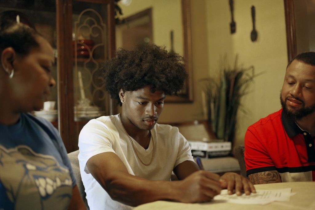 Second Place, Ron Kuntz Sports Photographer of the Year - Kyle Robertson / The Columbus DispatchColumbus South Trevell Adams signs a scholarship letter committing to play basketball at Ohio Dominican along side his parents Staci Rouse and Leavell Adams at his house in Columbus on June 25, 2020. Adam finished the season on the second team All-Ohio in Division I. 