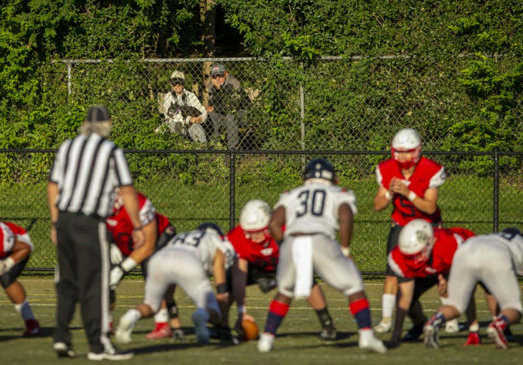Third Place, Ron Kuntz Sports Photographer of the Year - Adam Cairns / The Columbus DispatchBarb and Rick Weber, with their dog Sadie, take advantage of a hole in the greenery behind their condo to watch the high school football game between St. Charles Prep Cardinals and the Bishop Hartley Hawks at St. Charles Preparatory School in Columbus on Friday, Sept. 18, 2020. 