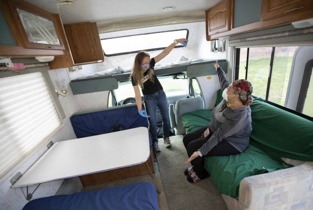 First Place, Team Picture Story - Adam Cairns / The Columbus Dispatch, “Social Distancing”Nursing home and home care nurse Julia Jalloh and Alice Foeller give each other a distancing hug inside Foeller's 1998 Shasta Cheyenne RV parked outside Jalloh's Northeast Side townhome on Tuesday, April 7, 2020. Foeller is loaning her RV to Jalloh to allow her to segregate herself from her family during the COVID-19 coronavirus pandemic to minimize their risk of being infected. 