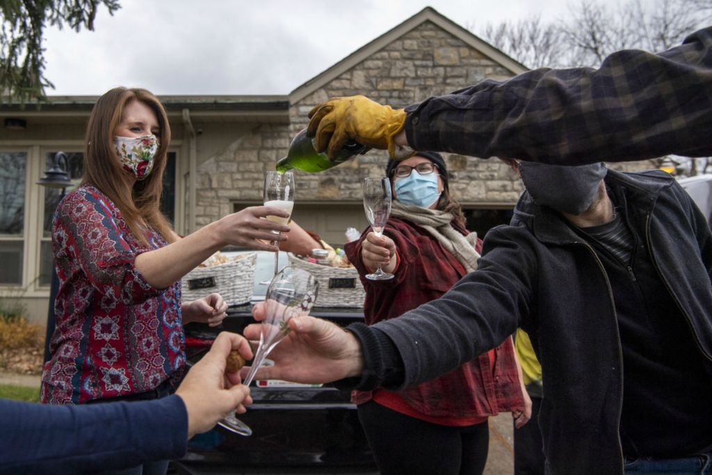First Place, Team Picture Story - Gaelen Morse / The Columbus Dispatch, “Social Distancing”Zane Jones, right, pours a glass of champagne for Kate Nelson, as their close group of friends exchange dishes in the Jones family driveway in place of their Friendsgiving tradition in Columbus, Ohio, on Nov. 26, 2020.