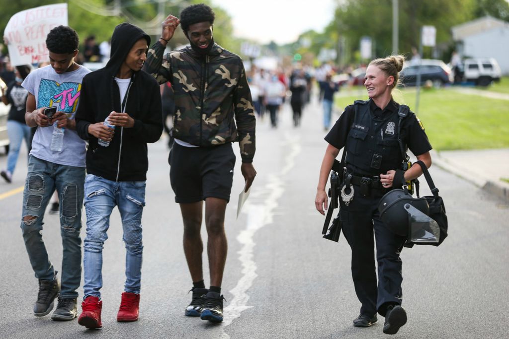 Second Place, Team Picture Story - Rebecca Benson / The Blade, “Protests Erupt”Toledo Police officer Nicole Tucker laughs with protesters on Hill Avenue during a BLM protest march in Toledo on Monday June 1, 2020. 