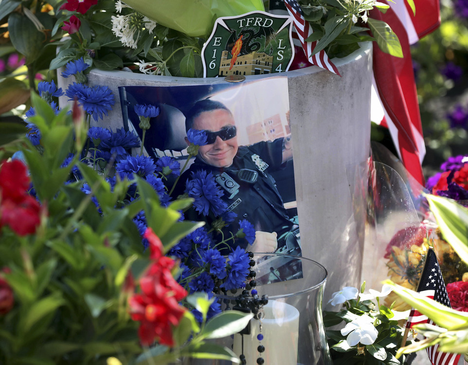 First Place, Team Picture Story - Amy E. Voigt / The Blade, “Officer Killed”A photograph of Toledo Police Officer Anthony Dia is surrounded by flowers and flags at a memorial setup in the Home Depot parking lot where he was killed.