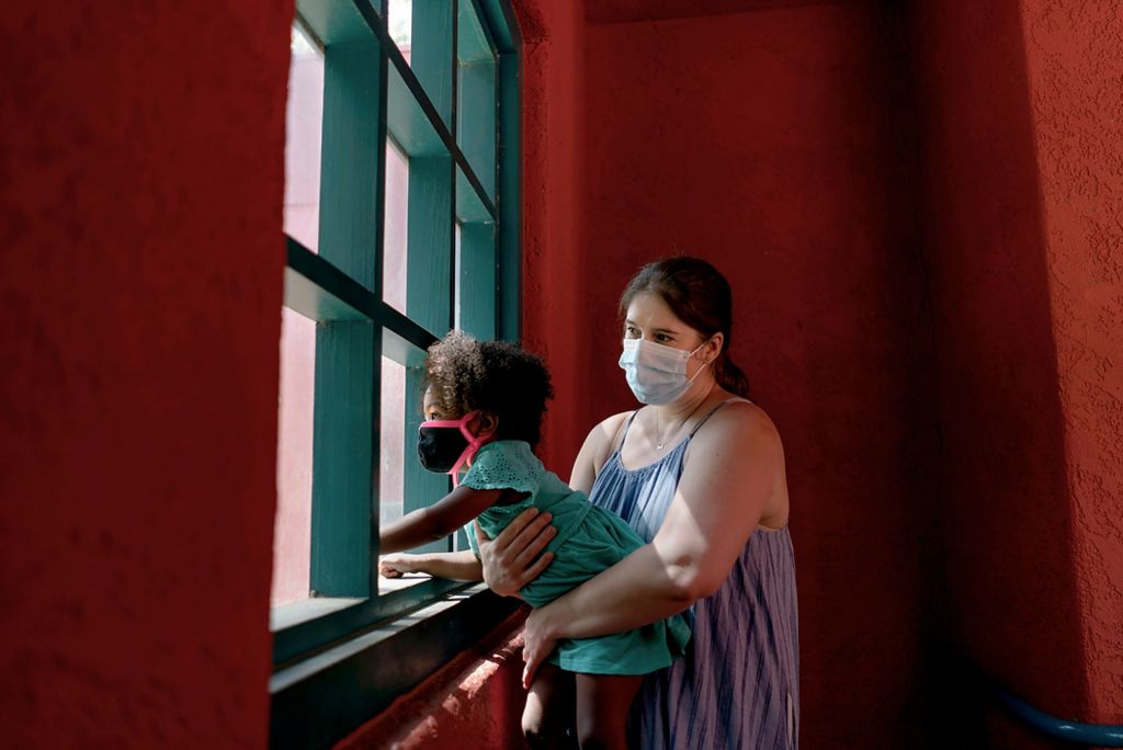 First place, Chuck Scott Student Photographer of the Year - Erin Burk / Ohio UniversityKristina Woldan holds her daughter, Zoë, up to a window at the Los Angeles Zoo in Los Angeles, California on June 10, 2021. Kristina Woldan is a full-time nurse, and has been caring for her adopted daughters Zoë and Okalani, who both have serious lung conditions, since she became their foster mother when Okalani was four months and Zoë was one months old. Due to their lung conditions, they are categorized as high-risk. Kristina worries that they would be hit hard by COVID-19 were they to catch it, and so has done her best to keep them safe and well-cared for through the hard times posed by the coronavirus pandemic.Zoë and Okalani rarely spend time with friends and virtually never go to playgrounds. On the rare occasion that happens, it’s an empty playground with masks still on and a change of clothes before getting back in the car. They haven't been able to return to pre-school either, just in case another kid not wearing a mask were to cough in one of their faces. The fight to protect them is all-encompassing, with Kristina working hard to keep them from having to battle an invisible adversary. "I don't know if they would survive COVID, but I'm trying really hard not to find out," she says.The nation's "return to normal" does not apply to everyone, and their family is among those who remain waiting for better days while the country reopens around them.