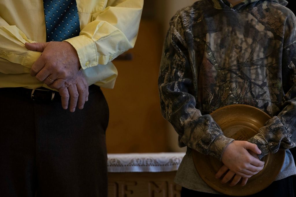 Second place, Chuck Scott Student Photographer of the Year - Chris Day / Ohio UniversityPastor Adelbert Winegardner Senior prays with Joey Henry, 13, at the front of Faith Baptist Church during a service before Henry walks around to collect money on Sunday, February 21, 2021. Winegardner and his wife turned portions of the closed down school in New Marshfield into a church after their former church was torn down. The school halls now hold memories of the many years of Sunday schools and services. On one wall, a canvas is filled with painted hands of children who now, as adults, bring their own sons and daughters to services.