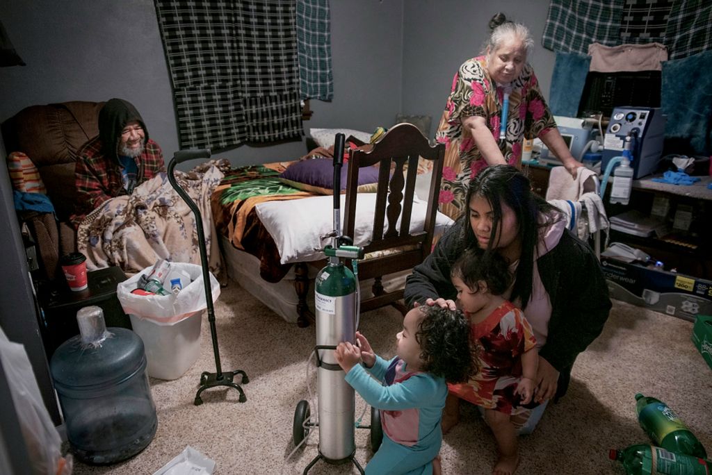 First place, Feature Picture Story - Erin Burk / Ohio University, "Medicare"Shellyanne Aknilang holds Aidrielyann and Amari back from playing with her grandmother, Lorene's, oxygen tank in Union City, Ohio, on November 11, 2021. It is very important in Marshallese culture that one’s parents are well taken care of. In the Joash family, both aging parents Jay and Lorene are cared for by their children and other younger relatives. With Lorene dealing with a tumor and Jay recovering from a stroke he experienced in 2017, the return of Medicare has greatly improved both their wellbeing and their children's ability to help them get the care they need. Lorene finds herself hospitalized frequently, although she would prefer to be home.