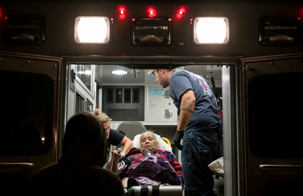 First place, Feature Picture Story - Erin Burk / Ohio University, "Medicare"Birash Joash, left, talks with his mother, Lorene, before she is taken to the hospital in Union City, Ohio, on October 20, 2021. Lorene has had ongoing health issues since the early 2010's. It began with asthma, which she received treatments for, but progressed to the point where she passed out and slipped into a coma during a routine visit with her family in Arkansas. She was comatose for eight months. Then, they found a tumor in her lung. Many Marshallese community members attribute their experiences with cancer to the Cold War-era testing in the Republic of the Marshall Islands. 