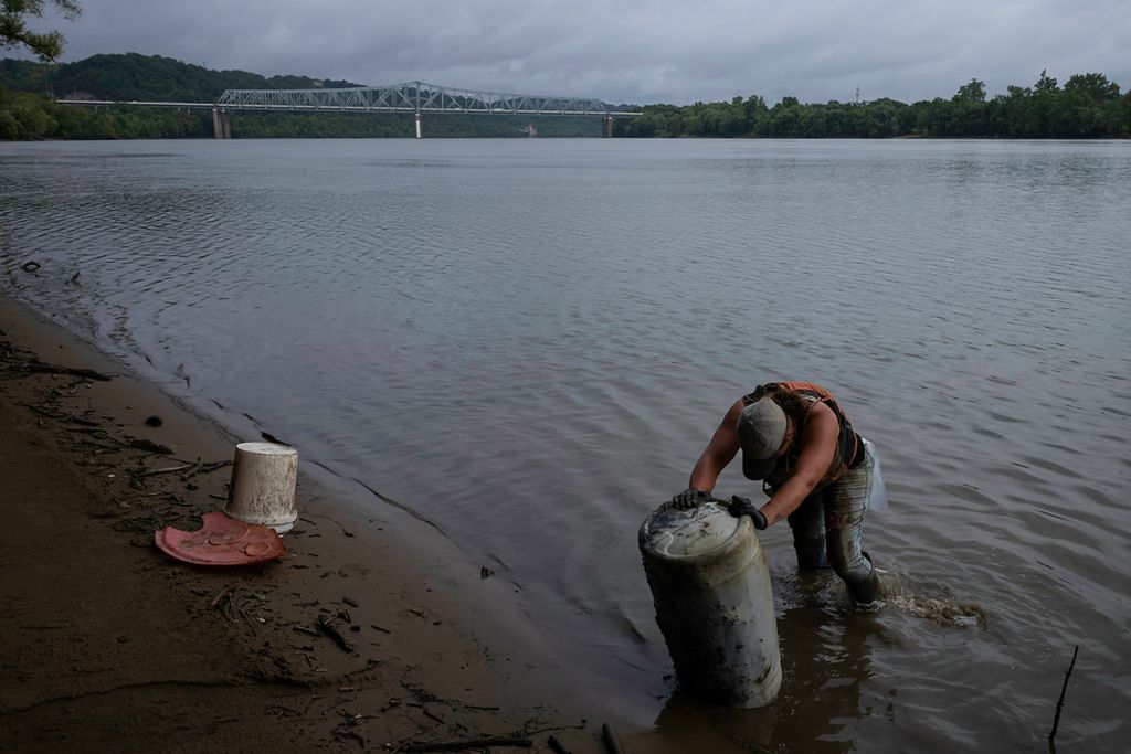 Second place, Feature Picture Story - Joshua A. Bickel / The Columbus Dispatch, "Our Rivers’ Keepers"Callie Schafer and Rachel Loomis are two women working with non-profit Living Lands and Waters, doing “industrial strength” river clean-up throughout the United States.  In 2021, the group collected over half a million pounds of trash across seven rivers throughout the U.S. Most of that garbage – 355,953 pounds, or 63% of it – came from the Ohio River. It’s a source of drinking water for over 5 million Americans and a body of water experts say is polluted by a layered and systematic “environmental death of a thousand cuts.”   The group is many things: A river clean-up, a band of modern-day deckhands living on a barge, educators who host watershed conservation initiatives and workshops and even, a group of tree-planters. “Recycling should be marketed as patriotic,” said founder Chad Pregracke. “And I think if more people thought about conserving America’s resources in that way, more would do it.” Over the last two decades, the group has carved out a small pocket of positive change. Driven by hard work, education and empathy, their mission not just environmental restoration, but a bonding experience between each other and our natural resources along the river towns and muddy shorelines of rural America. “This is one of those cool things that creates an outlet for people to do good,” Pregracke said.Callie Schafer works to remove a mud and rock-filled plastic barrel from the Ohio River while working near Cincinnati. The barrel, which weighed about 300 pounds, was too heavy for Schafer and colleague Rachel Loomis to remove. They planned to come back and remove it with an excavator they keep on a river barge where they live and work.