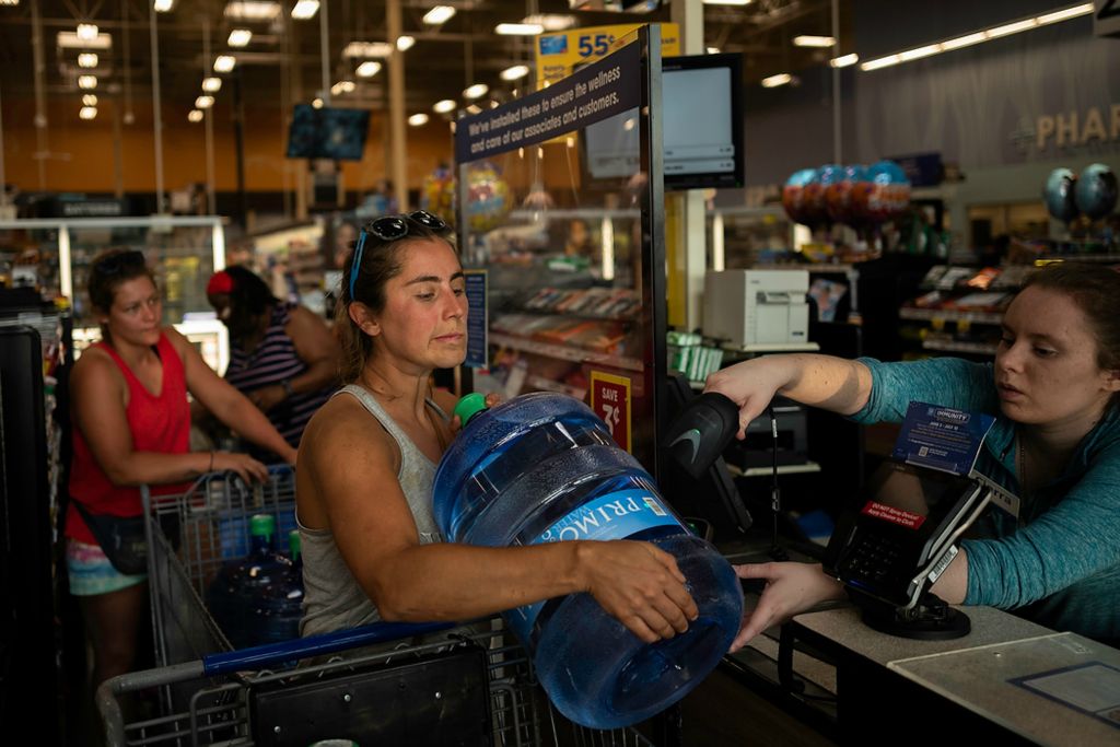 Second place, Feature Picture Story - Joshua A. Bickel / The Columbus Dispatch, "Our Rivers’ Keepers"Rachel Loomis holds up a water jug as they check out at a Kroger in Cincinnati. Though they live on the barge, they rely on a fleet of land-based trucks and trailers to move supplies from one town to the next. On slow days, the crew heads into the nearest town for water, gas and food, which is then hauled back to their home on the barge.