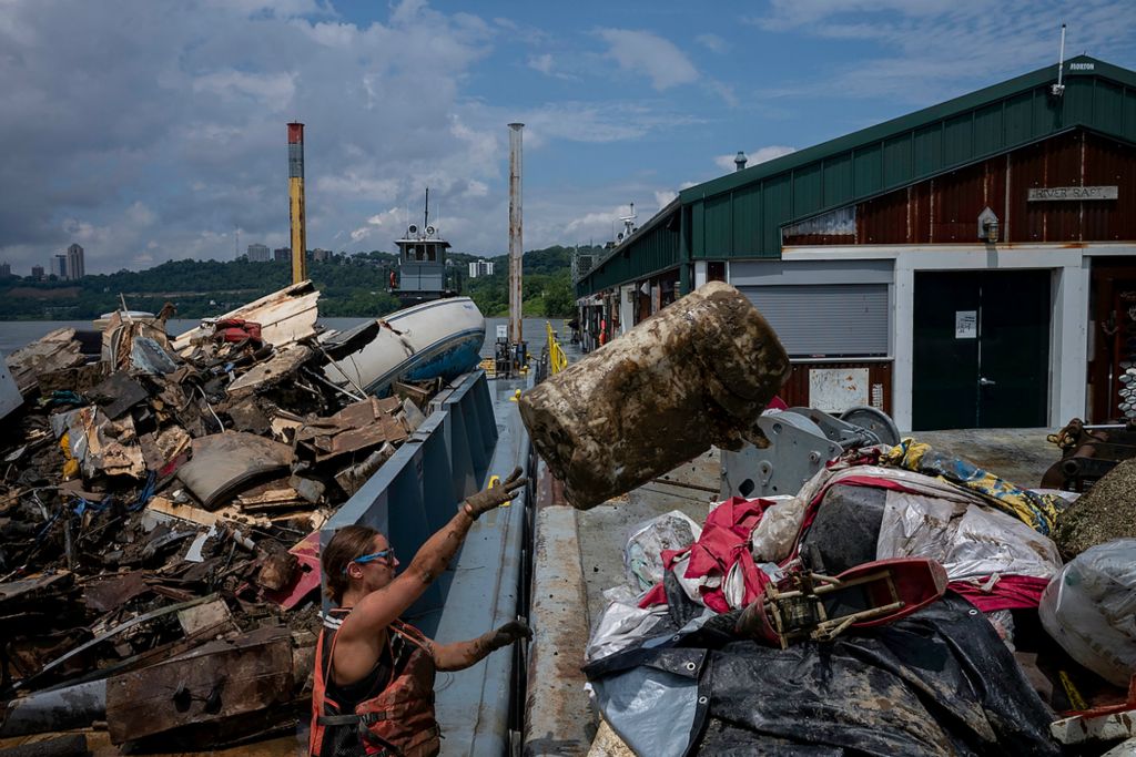 Second place, Feature Picture Story - Joshua A. Bickel / The Columbus Dispatch, "Our Rivers’ Keepers"Rachel Loomis tosses a plastic barrel onto the barge after a morning clean-up in Cincinnati. As trash is gathered, it's brought back to their barge, where they sort and store it before disposing of it properly. Their operation is made up of 21,000 square feet of barges: There’s one for humans, the house barge, two for trash, scrap metal and plastics and one for their excavator. In 2021, the group removed 355,953 pounds of garbage from the Ohio River.