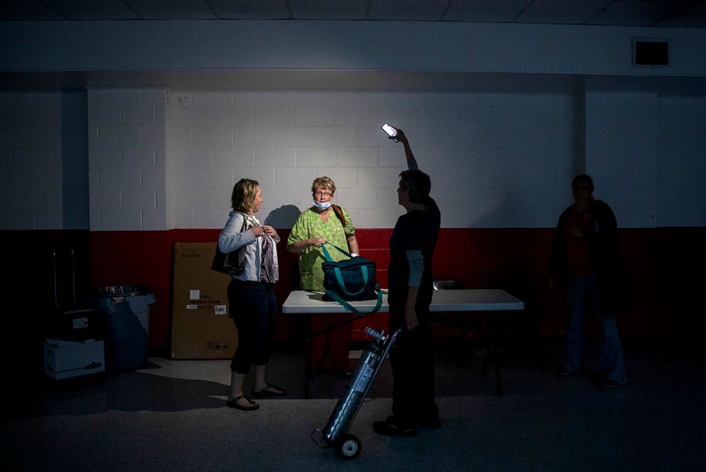 Third place, Feature Picture Story - Meg Vogel / The Cincinnati Enquirer, "Vaccine Hesitancy"Jennifer Profitt, president of Franklin County's health board,  uses her cell phone as a flashlight after a squirrel chewed an electrical line and knocked out power at the temporary vaccination clinic at the Laurel Community Center on June 7, 2021 in Laurel, Indiana. Profitt wanted to keep the clinic running for another hour or two. They still had plenty of vaccine vials in the cooler, but they can’t give shots in the dark.