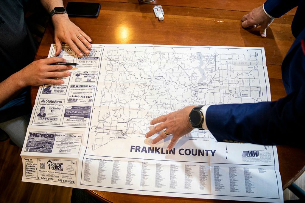 Third place, Feature Picture Story - Meg Vogel / The Cincinnati Enquirer, "Vaccine Hesitancy"Dr. Thomas Huth, vice president of medical affairs for Reid Health, and Jonathan White, vice president of White's Farm and pharmacist, look at a map of Franklin County, Indiana and discuss the challenges of accessibility for the rural parts of the county on June 2, 2021 in Brookville, Indiana. White started to feel the pandemic's lasting impact when he saw his patients' names in the obituaries. He is working with the Franklin County Health Department to bring the vaccine to people, like his weekly flea market. Accessibility and trust are two challenges Franklin County is battling as vaccine rates remain low.