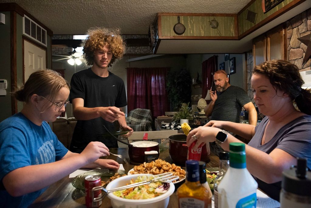 Award of Excellence, Feature Picture Story - Alie Skowronski / Ohio University, "New Normal"From left: Joslynn, her brother Jaylen Mayhew, her stepfather Aaron, and Jodi have dinner in their home in Wheelersburg, Ohio, on June 7, 2021. The family spends most of their days together and the kids help out at the family’s shop. “We kept Joslynn close to us after her surgery, and we just got used to always having her around,” said Aaron.