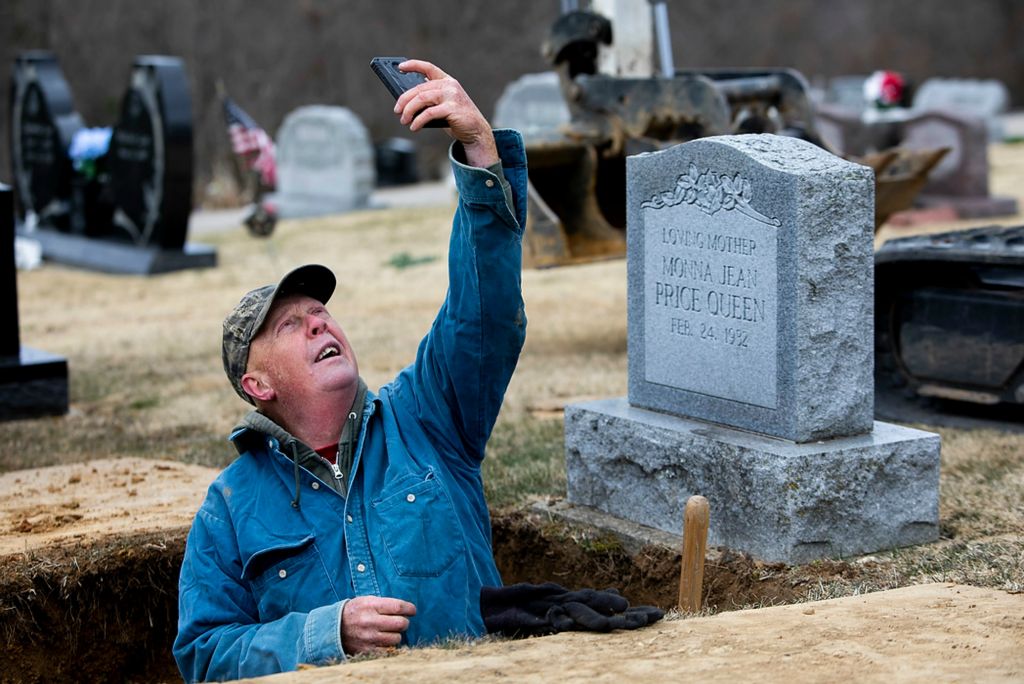 Second place, News Picture Story - Chris Day / Ohio University, "New Marshfield, Ohio"Bruce Chaney tries to get reception on his phone after he finishes digging a grave to check the weather and see if he will need to cover the hole from rain on March 15, 2021. Chaney has worked for the Waterloo Township since 2004 and has looked after the New Marshfield cemetery ever since. He said he helped bury his mother and father during his first year on the job.