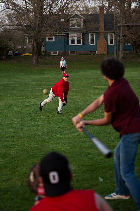 Second place, News Picture Story - Chris Day / Ohio University, "New Marshfield, Ohio"Andrew Wheeler, 15, throws a pitch while Addam Eblin, 15, sits ready to catch it as DJ Gonzalez begins to swing at it on April 4, 2021. Kids and teenagers often bike throughout the town and play in the field and park at the center of town as parents and friends watch from the surrounding houses.