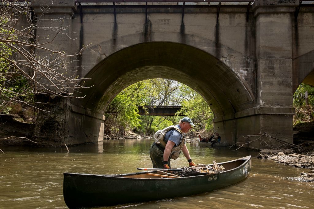 Second place, Photographer of the Year - Large Market - Meg Vogel / The Cincinnati EnquirerDave Schmitt, Executive Director of the Mill Creek Alliance, walks his boat to the bank of the Mill Creek to pick up trash and debris during a clean-up in Evendale on Friday, April 16, 2021. In 1997, more than two decades after the Clean Water Act, the Mill Creek was declared the most polluted and endangered urban stream in North America. Some thought it was a lost cause. But not everyone. The Mill Creek Yacht Club has been working to restore the creek since 1994. Now, dozens of species of fish call the Mill Creek home.