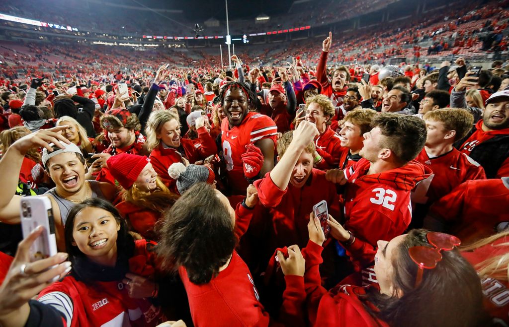 Third place, Photographer of the Year - Large Market - Adam Cairns/Columbus Dispatch / Ohio State Buckeyes defensive end Zach Harrison (9) makes his way through fans that stormed the field following the 33-24 win over the Penn State Nittany Lions in the NCAA football game at Ohio Stadium in Columbus on Oct. 31, 2021. 