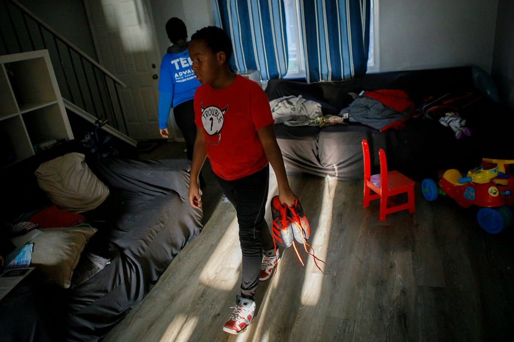 Third place, Photographer of the Year - Large Market - Adam Cairns / The Columbus DispatchChristian McNair, 10, gathers his soccer cleats to get ready to play on the field at Havenwood Townhomes in the Hilltop on Nov. 22. Soccer is a popular hobby for many of underprivileged kids in the Hilltop like Christian. My Project USA funds the Hilltop Tigers program to keep kids active and out of trouble year round.