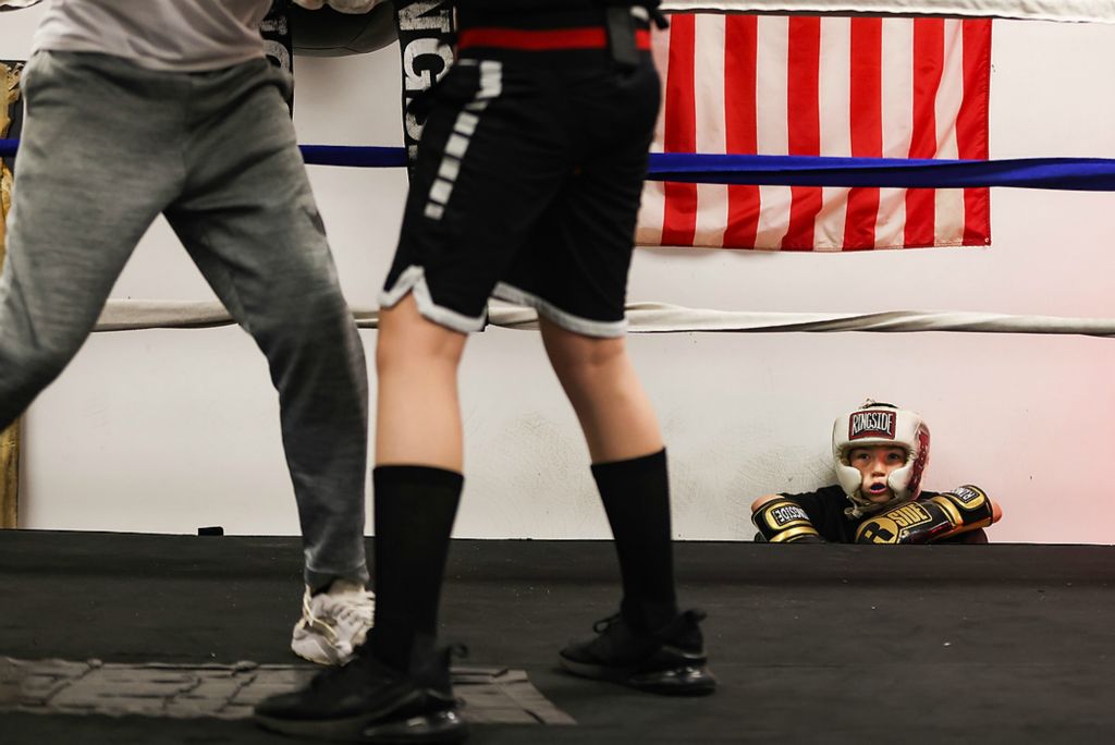 First place, Ron Kuntz Sports Photographer of the Year - Rebecca Benson / The BladeJuan Martinez, 7, sits under an American flag as he watches his classmates spar at the Believe Center in Toledo on March 25, 2021.