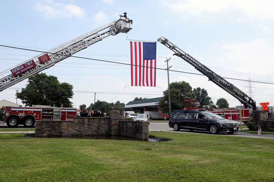 News Picture Story - Second Place, “Korean War Vet”An American flag hangs between Genoa Township and Westerville fire engines as a hearse carrying the remains of Korean War Army veteran private first class Jack E. Lilley passes underneath June 14, 2022, at Northlawn Memory Gardens in Westerville.   (Shane Flanigan / ThisWeek Community News)