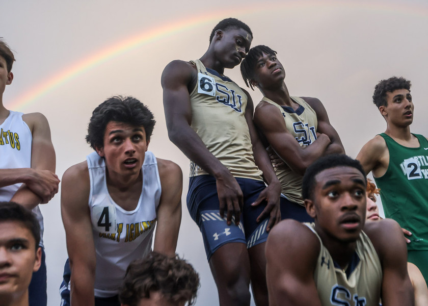 Sports Feature - First Place, “Rainbow”St John's Jesuit Titans long-distance runners Joseph Taylor, (top left) and teammate Caleb Kelly huddle together for a conversation while awaiting to be crowned champions of the 4x400 relay qualifying team for states during the OHSAA Division I track and field regional track meet at Findlay High School. (Isaac Ritchey / The Blade)