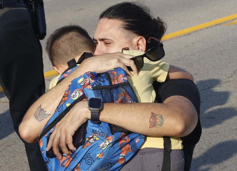 Award of Excellence - Photographer of the Year - Small Market A father hugs his son at the scene of a Northwestern School District bus crash that killed one student and injured more than 20 others on State Route 41 near Springfield, Ohio Tuesday, August 22, 2023. The bus, carrying 52 elementary students on their way to the first day of school was struck by a mini van and rolled over.  (Bill Lackey / Springfield News-Sun)
