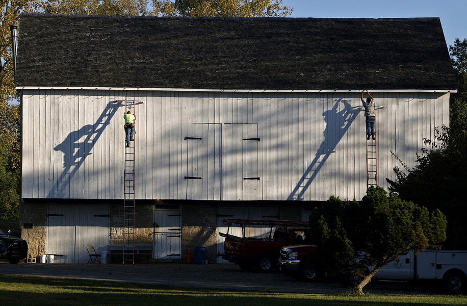 Award of Excellence - Photographer of the Year - Small Market Two workers from Enterprise Roofing cast their shadows on the side of the barn at George Rogers Clark Park as they install brackets to hold a new copper cutter on the barn Tuesday, Oct. 3, 2023.  (Bill Lackey / Springfield News-Sun)