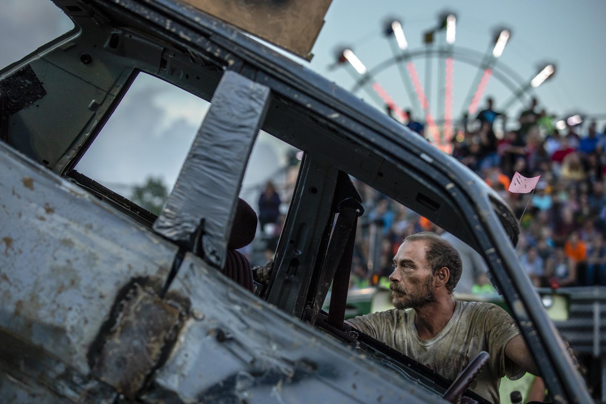 A demolition derby driver examines his car after it was pushed up and onto a concrete barrier during his heat at the 160th Portage County Fair, August 21, 2018.