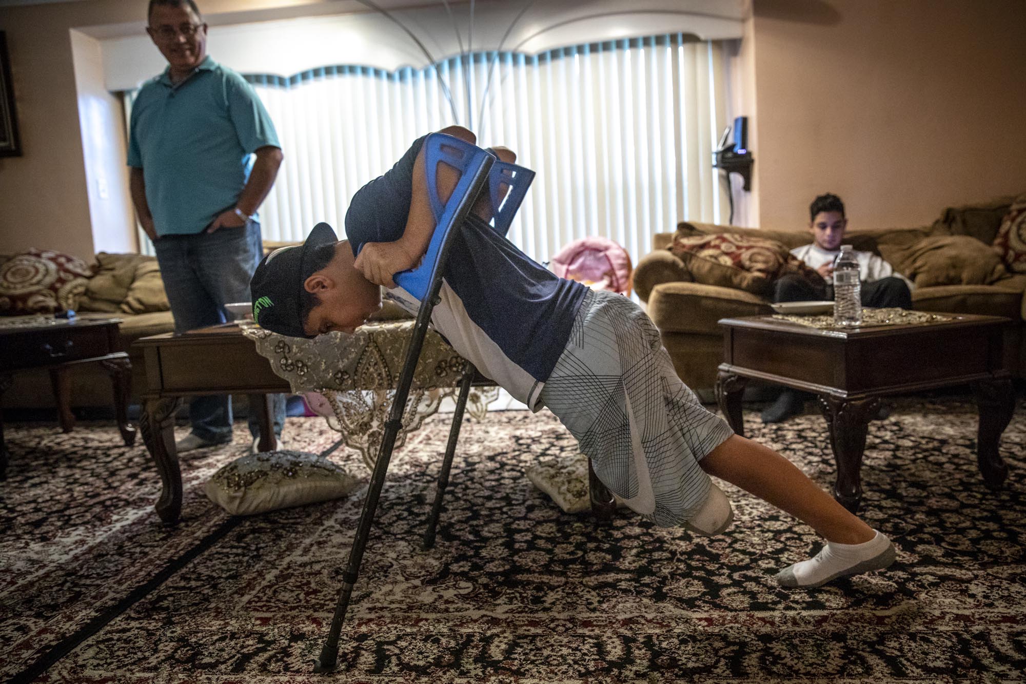 Abood does pushups on his crutches in the Mousa’s family room.