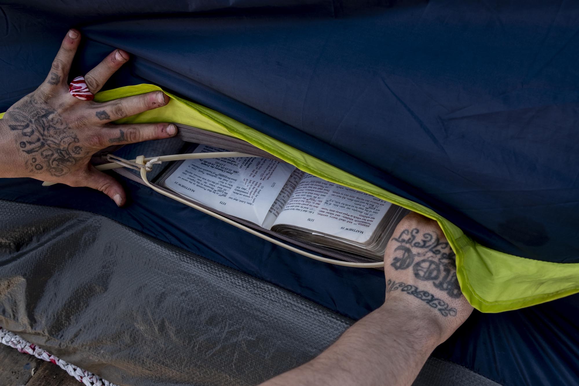 Dustin opens the door of his tent to retrieve his bible. Many of the homeless who live at Tent City complain that too many of the charities helping homeless people in the Akron area force religion. Dustin is not one of them.