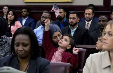 Dunya Al Haek gently kisses her son Mousa as he absentmindedly waves an American flag in the air at his father's naturalization ceremony in Columbus. The family arrived in Ohio eight years ago on a green card. Mousa, 5, was born in Ohio. His two older sisters, Dima and Maryam will receive their citizenship after their parents have theirs.